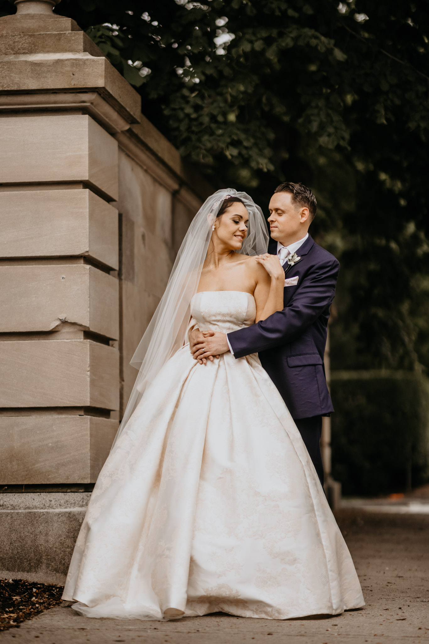 Cinematic portrait of a couple embracing in front of a stone mansion